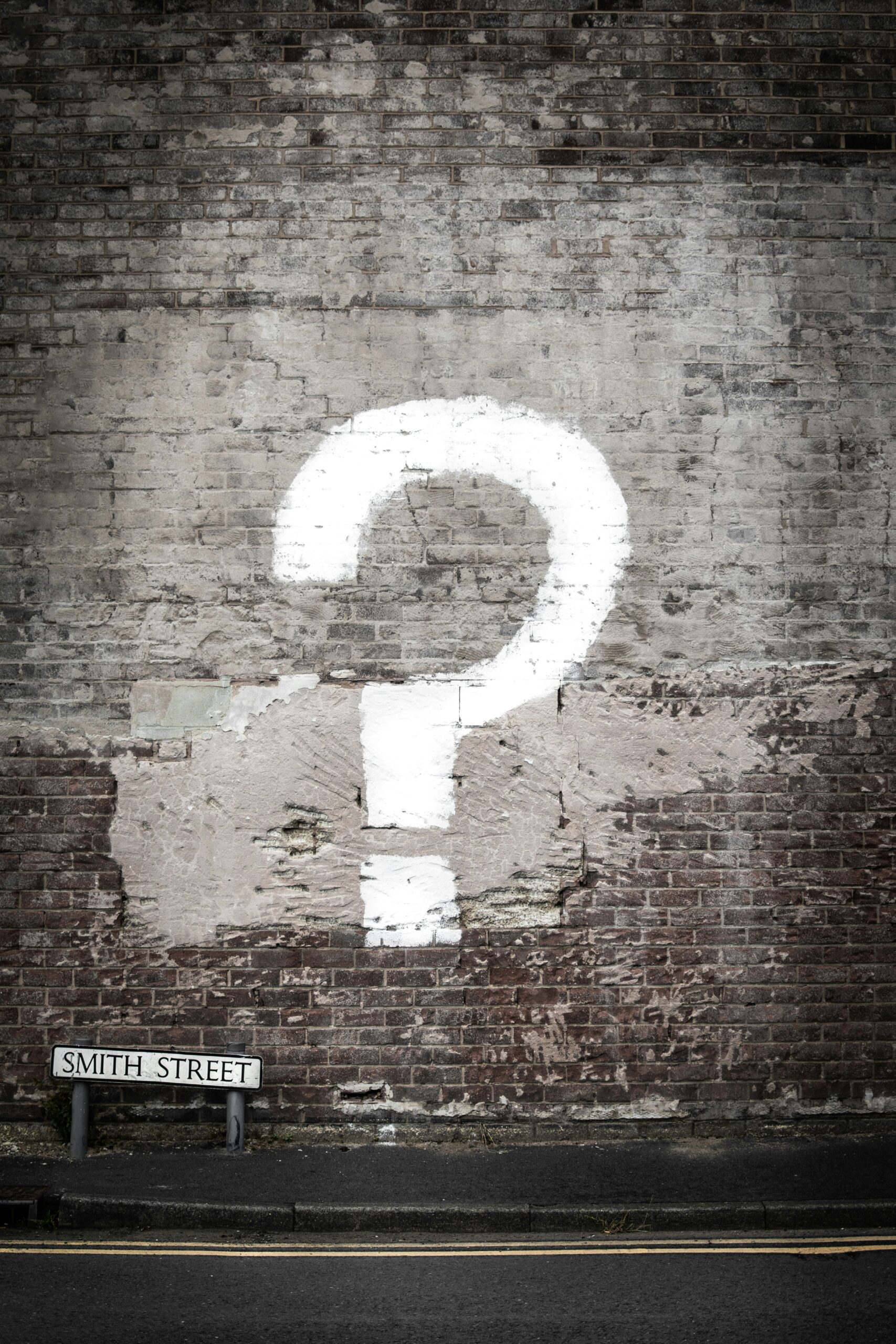 A question mark on a rustic brick wall indicating frequently asked questions about the best online thrift stores