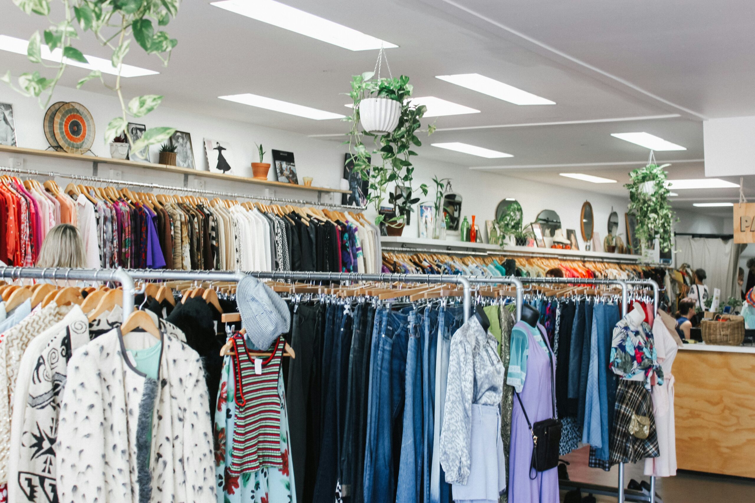 A thrift store with racks of clothing, shelves of knick-knacks, and bins of shoes. 