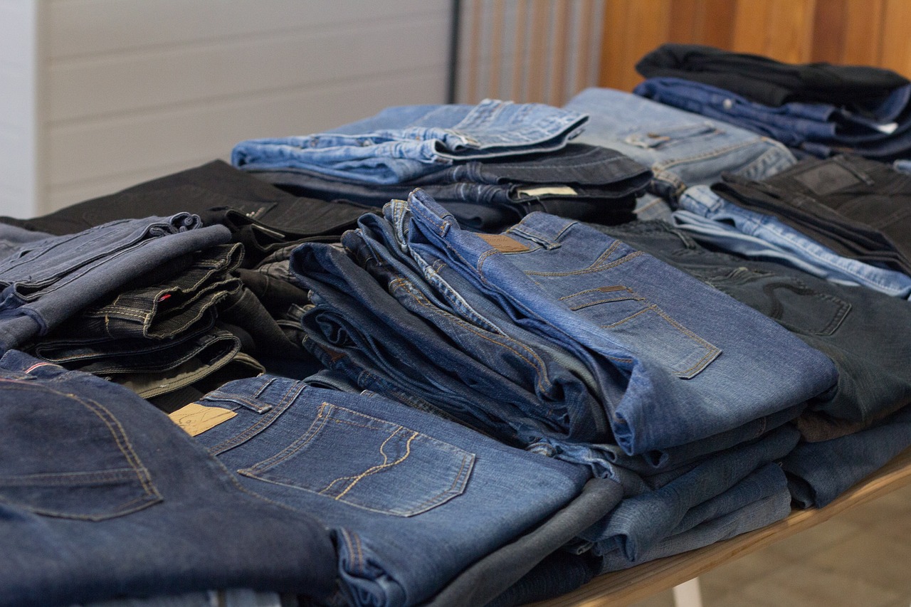 several pairs of jeans stacked on table at a thrift store