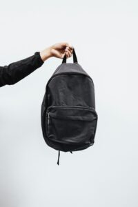 recycled material backpack being held by hand suspended in air