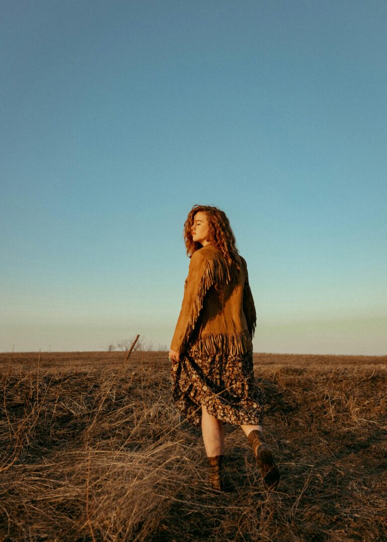 Back View of Redhead Girl Standing in Field wearing a suede jacket